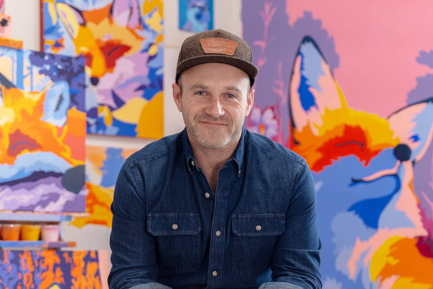 Man sitting in front of colorful fox paintings